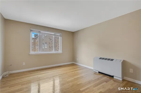 a view of an empty room with a window and wooden floor