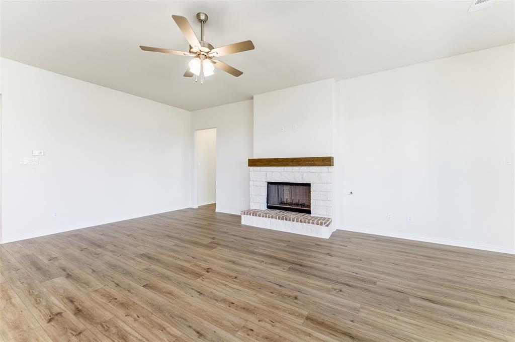 1030 County Road 200 Valley View, TX 76272 - Photo 15 of 27 Unfurnished living room with a fireplace, light wood finished floors, and a ceiling fan