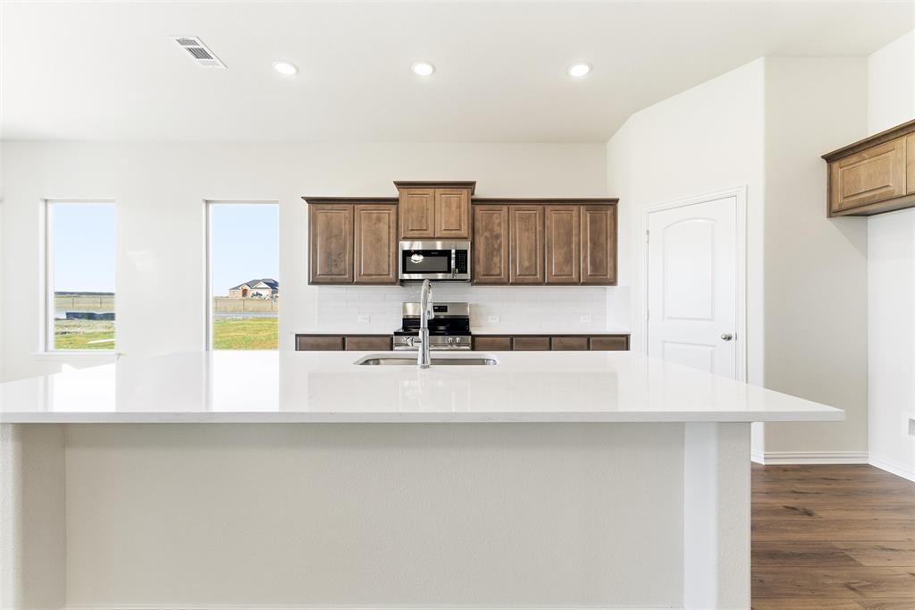 1030 County Road 200 Valley View, TX 76272 - Photo 17 of 27 Kitchen with a large island with sink, light stone counters, recessed lighting, appliances with stainless steel finishes, and brown cabinetry