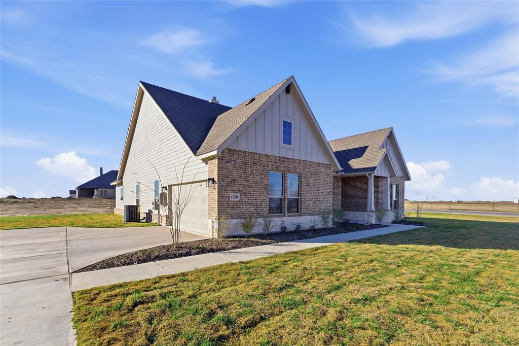 1030 County Road 200 Valley View, TX 76272 - Photo 3 of 27 View of front facade with board and batten siding, brick siding, concrete driveway, a front lawn, and a shingled roof