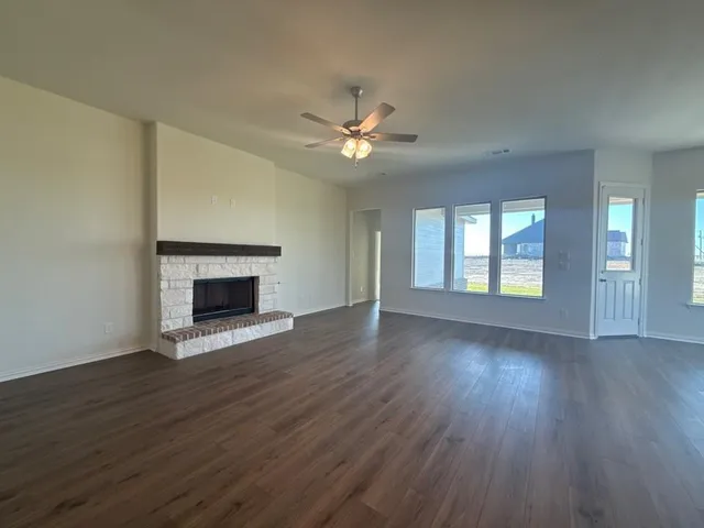 a view of an empty room with wooden floor fireplace and a window