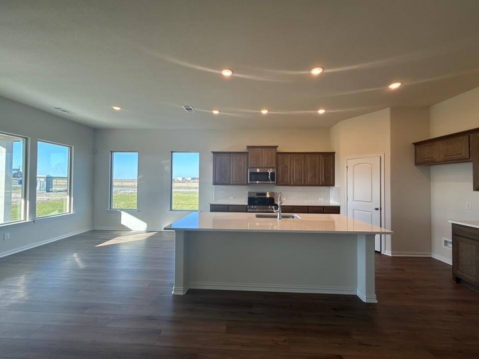 1030 County Road 200 Valley View, TX 76272 - Photo 4 of 8 a view of kitchen with stainless steel appliances granite countertop a stove top oven a sink and a refrigerator with wooden floor