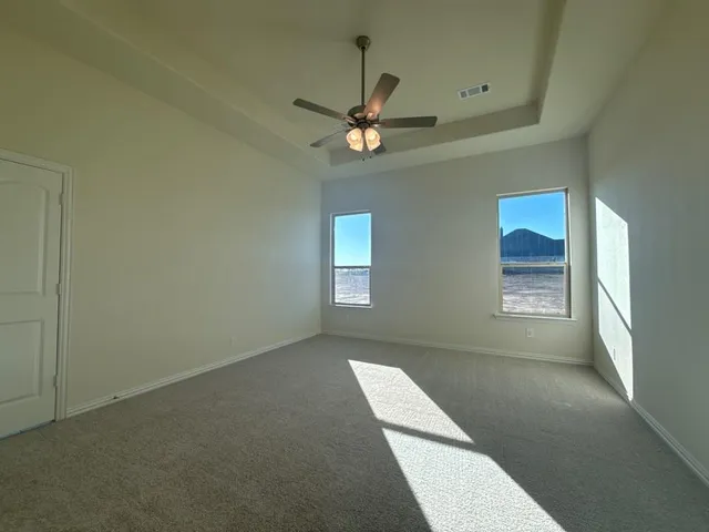an empty room with windows and fan