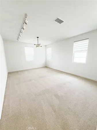 an empty room with a chandelier fan and windows