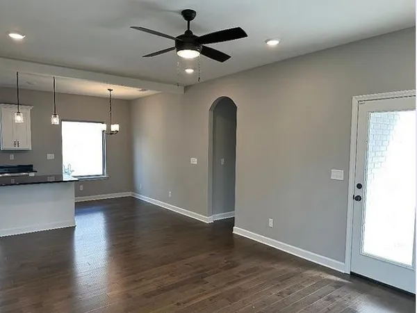 an empty room with wooden floor and a ceiling fan