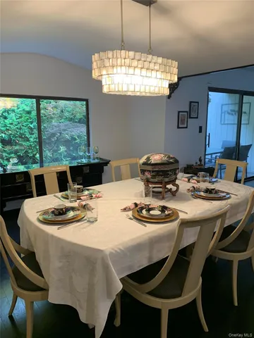 a dining room with furniture a chandelier and a large window