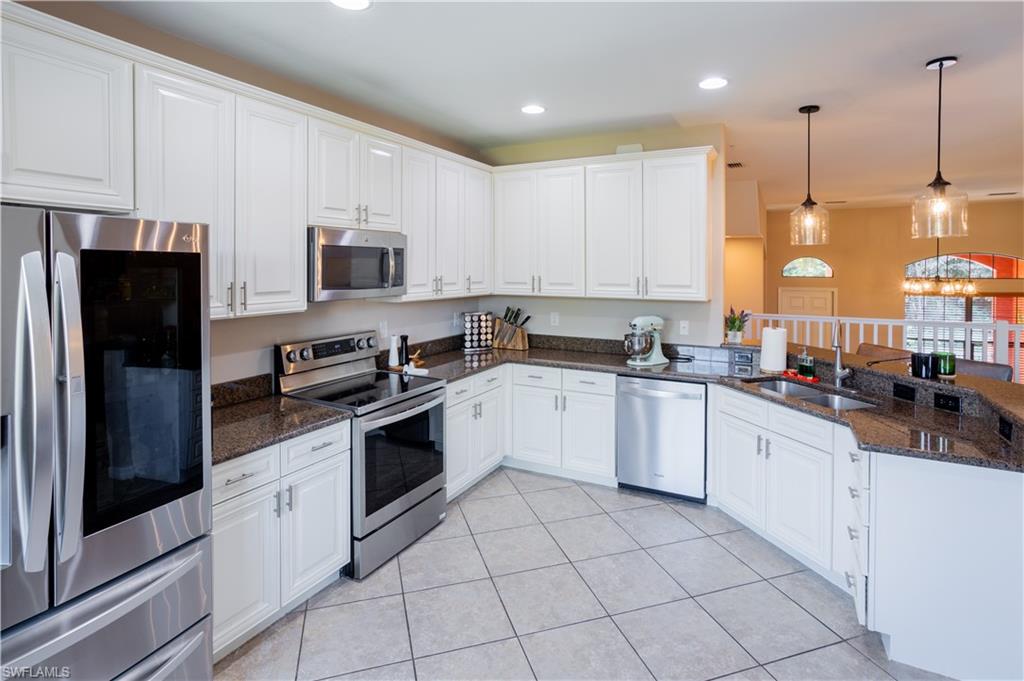 9063 Capistrano Street North, Unit 4408 Naples, FL 34113 - Photo 14 of 50 a kitchen with stainless steel appliances granite countertop a refrigerator a sink and white cabinets