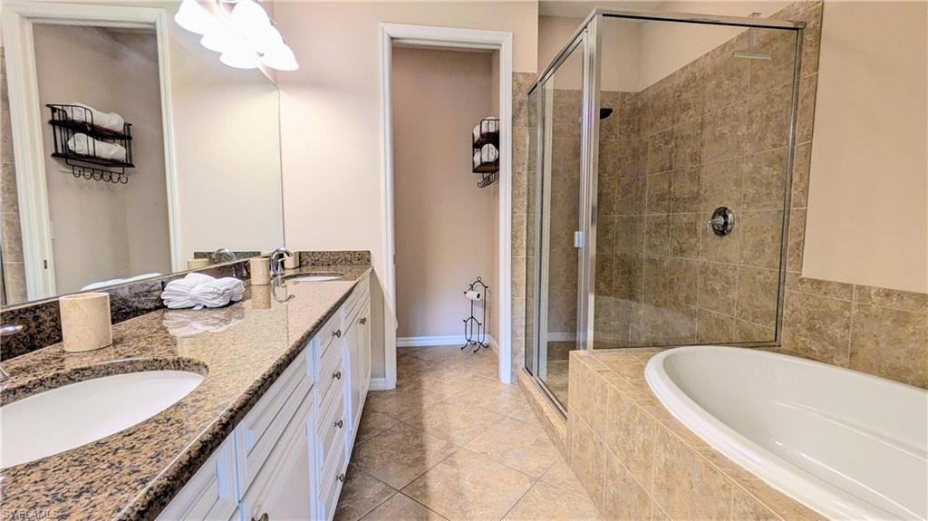 9063 Capistrano Street North, Unit 4408 Naples, FL 34113 - Photo 21 of 50 a bathroom with a granite countertop tub sink and mirror