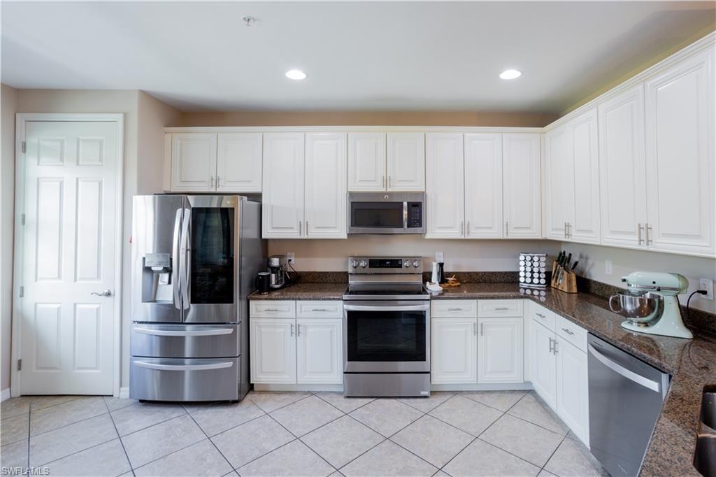 9063 Capistrano Street North, Unit 4408 Naples, FL 34113 - Photo 4 of 50 a kitchen with white cabinets and stainless steel appliances