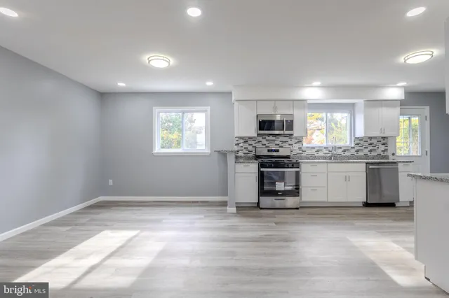 a kitchen with granite countertop a stove top oven and cabinets