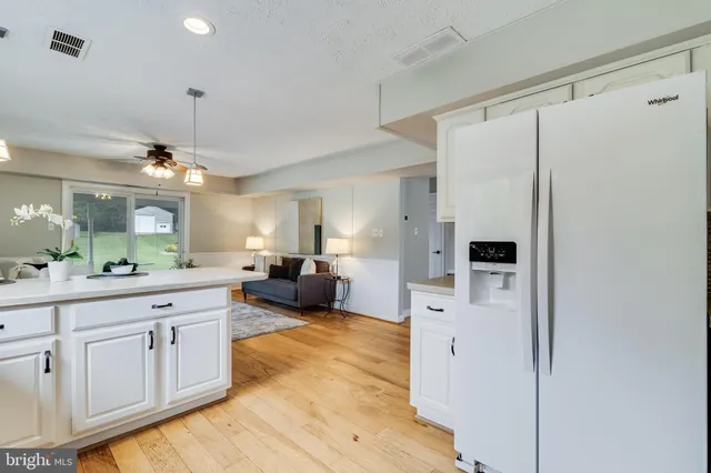 a large white kitchen with a refrigerator a stove a sink dishwasher and white cabinets with wooden floor