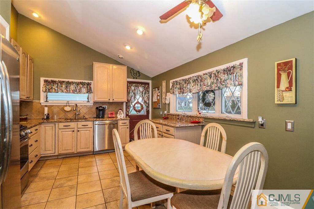11 Westminster Road Colonia, NJ 07067 - Photo 6 of 24 a kitchen with stainless steel appliances granite countertop a stove a refrigerator a sink dishwasher a dining table and chairs with wooden floor
