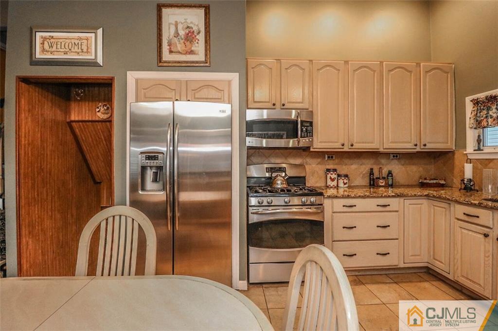 11 Westminster Road Colonia, NJ 07067 - Photo 7 of 24 a kitchen with stainless steel appliances granite countertop a refrigerator a stove and a sink with wooden floor