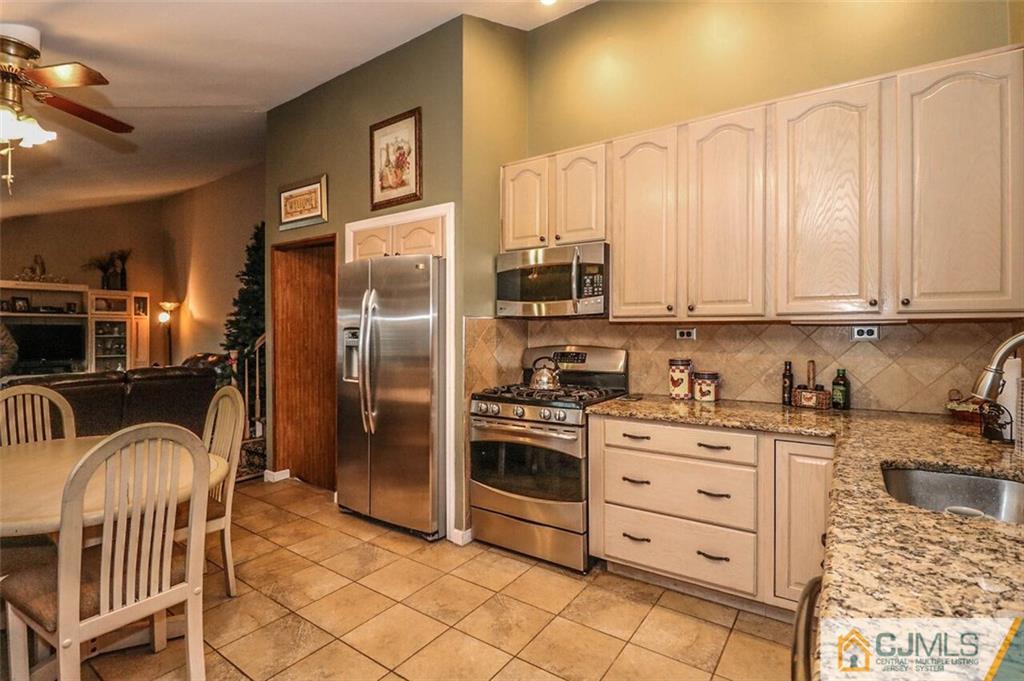 11 Westminster Road Colonia, NJ 07067 - Photo 8 of 24 a kitchen with stainless steel appliances granite countertop a refrigerator a stove a sink and white cabinets with wooden floor