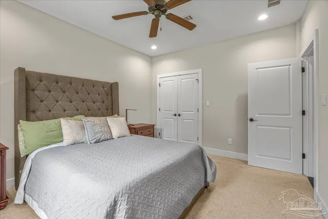 a bedroom with a large bed and ceiling fan