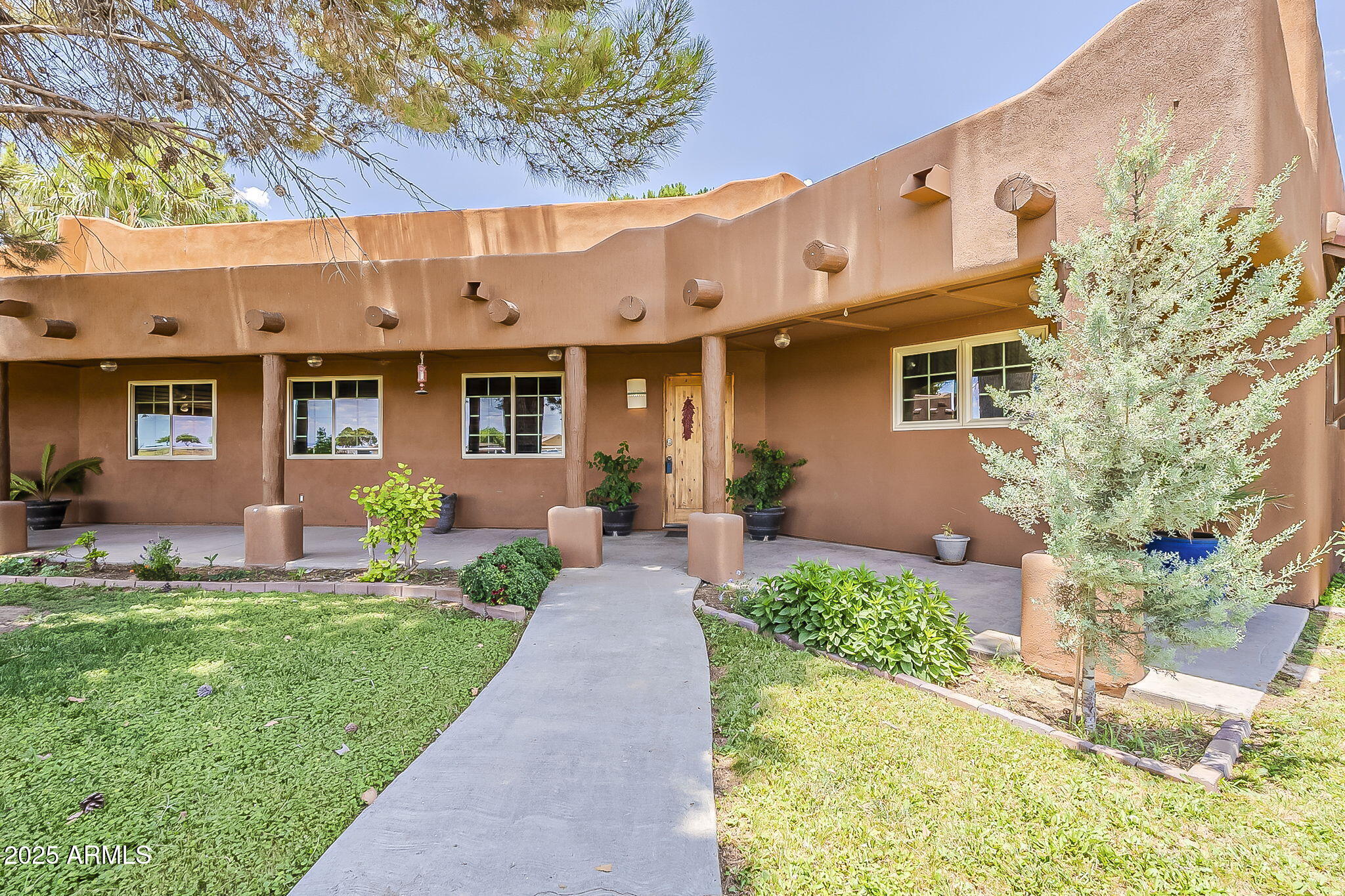 a front view of a house with a yard and potted plants