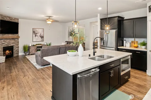 a kitchen with stainless steel appliances granite countertop a sink a microwave oven and a dining table with wooden floor