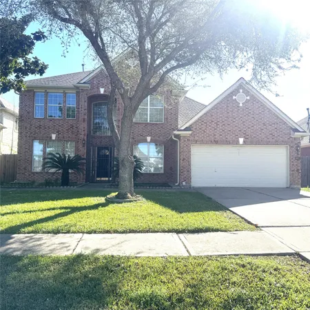 a view of a house with a yard and a large tree