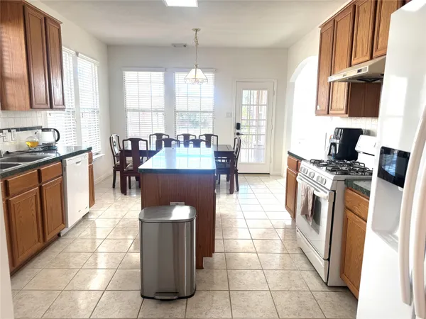a large kitchen with stainless steel appliances a stove a sink a counter top space and cabinets