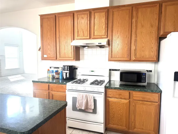 a kitchen with stainless steel appliances granite countertop a stove a sink and a microwave