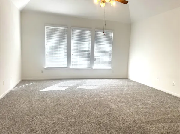 an empty room with a fan & a window
