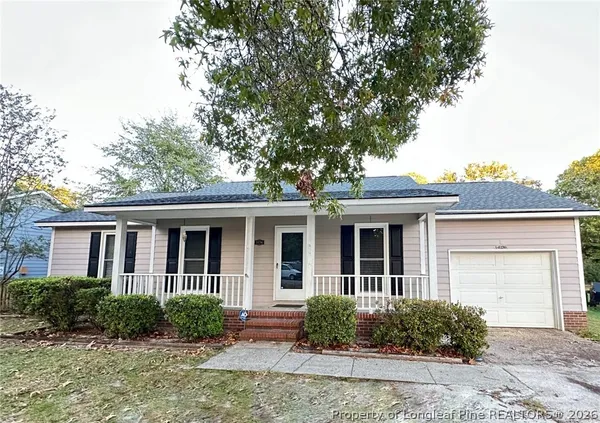 front view of house with potted plants and a large tree