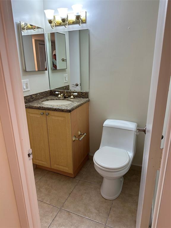 1900 South Ocean Boulevard, Unit 7J Lauderdale-by-the-Sea, FL 33062 - Photo 9 of 30 a bathroom with a granite countertop toilet and a sink
