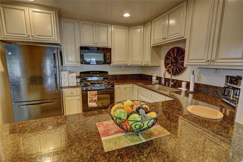22221 Bloomfield Street, Unit 47 Cypress, CA 90630 - Photo 27 of 30 a kitchen with stainless steel appliances granite countertop a refrigerator a stove top oven a sink and dishwasher