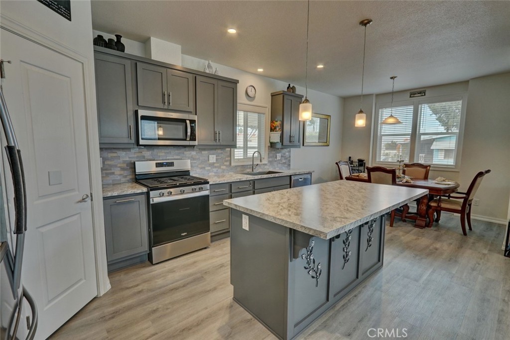 22221 Bloomfield Street, Unit 47 Cypress, CA 90630 - Photo 6 of 30 a kitchen with stainless steel appliances granite countertop a kitchen island hardwood floor sink stove dining table and chairs
