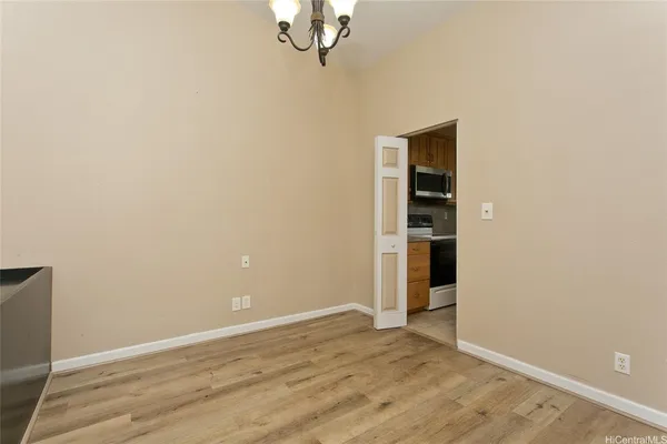 an empty room with wooden floor cabinet and windows