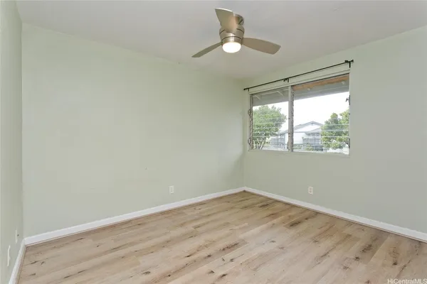 a view of empty room with wooden floor and fan