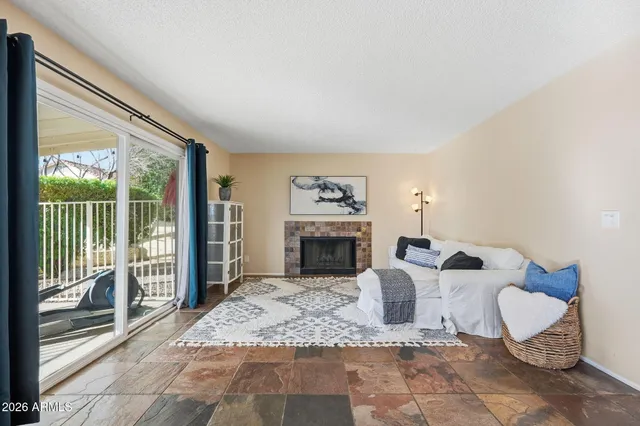 a living room with furniture a fireplace and a floor to ceiling window
