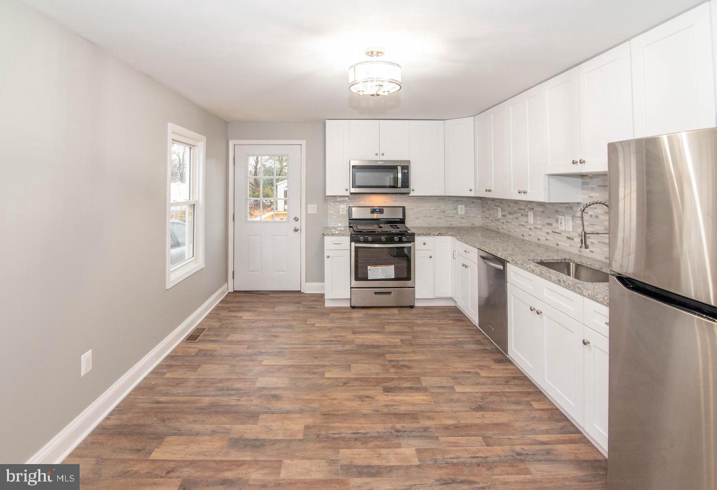 913 Wise Avenue Baltimore, MD 21222 - Photo 2 of 11 a large kitchen with stainless steel appliances granite countertop a stove top oven a refrigerator a sink and dishwasher with white cabinets