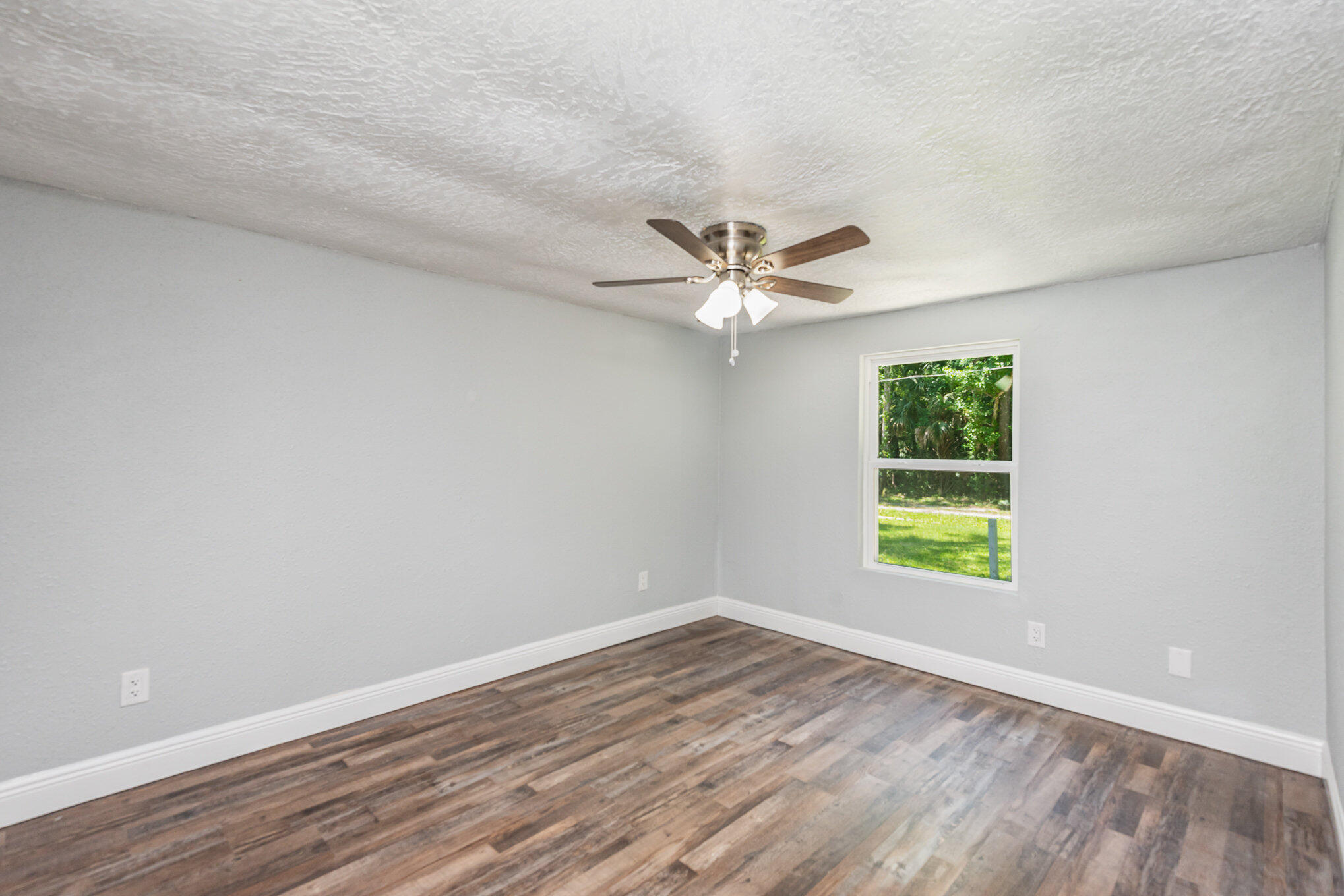 24050 Bass Road Astor, FL 32102 - Photo 16 of 22 wooden floor in an empty room with a window