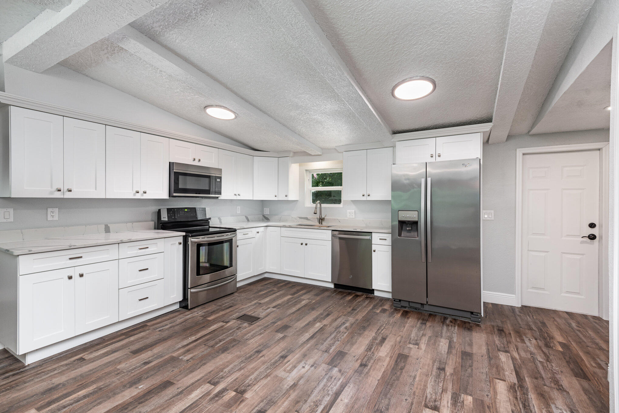 24050 Bass Road Astor, FL 32102 - Photo 5 of 22 a kitchen with white cabinets stainless steel appliances and sink