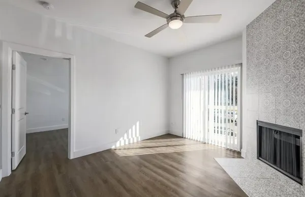 an empty room with wooden floor fan and windows