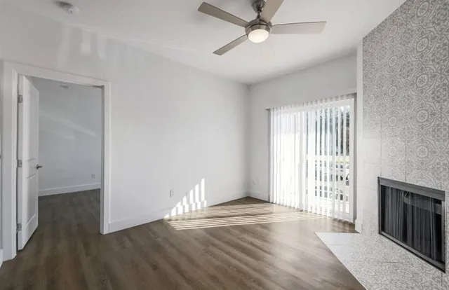 an empty room with wooden floor fan and windows