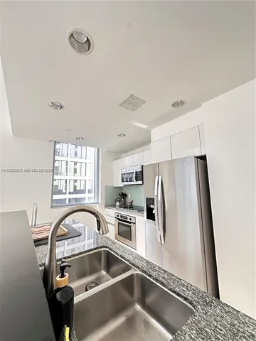 a close view of a sink a refrigerator and window