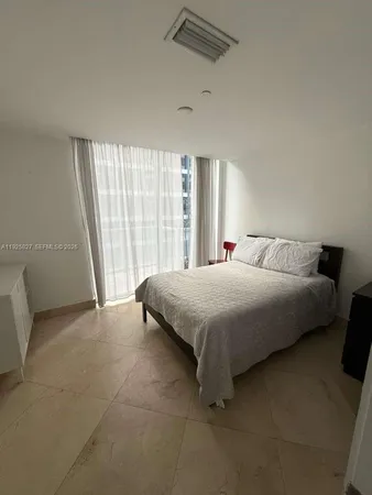 a spacious bedroom with a bed and a large window