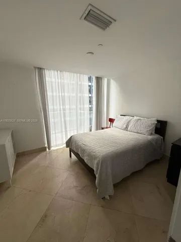 a spacious bedroom with a bed and a large window