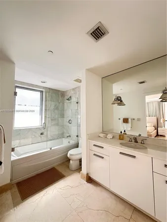 a bathroom with a granite countertop sink mirror vanity bathtub and a toilet