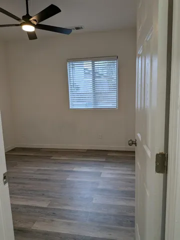 an empty room with wooden floor closet and windows