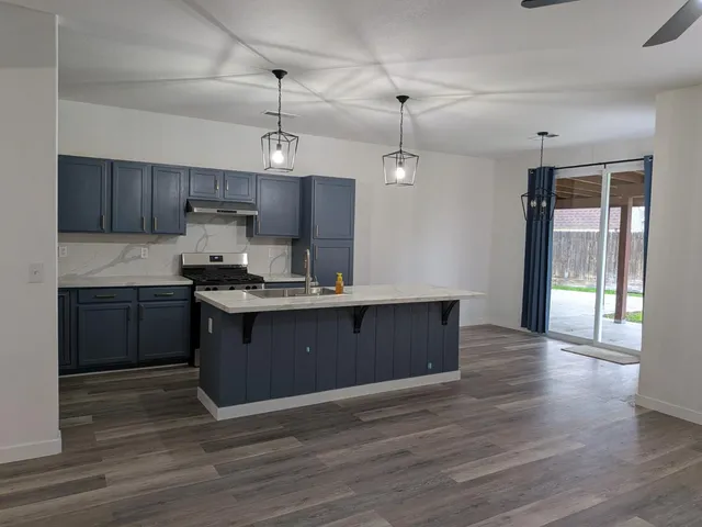 a kitchen with granite countertop a stove a sink and a refrigerator