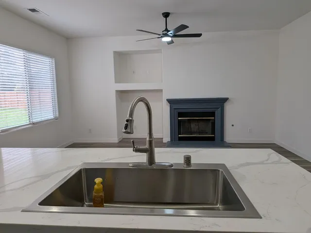 a kitchen with stainless steel appliances a sink a stove a refrigerator and chairs