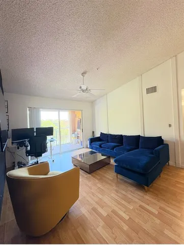 a living room with couches and kitchen view with wooden floor
