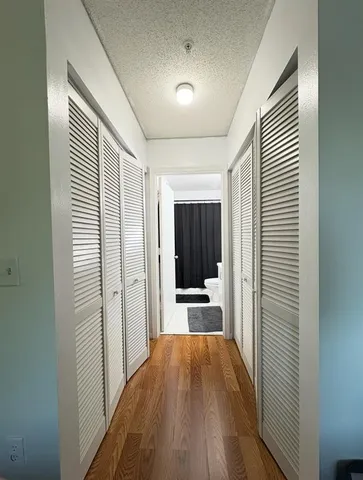 a view of a hallway with wooden floor cabinets and a kitchen