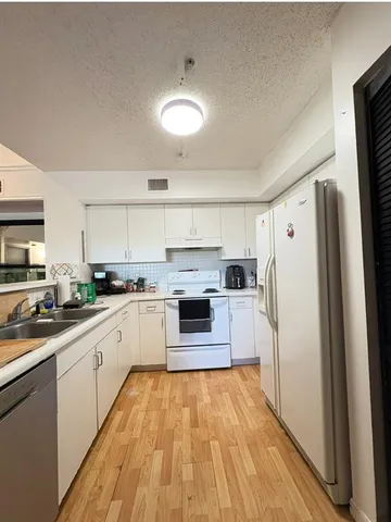 a kitchen with granite countertop a refrigerator and a stove top oven