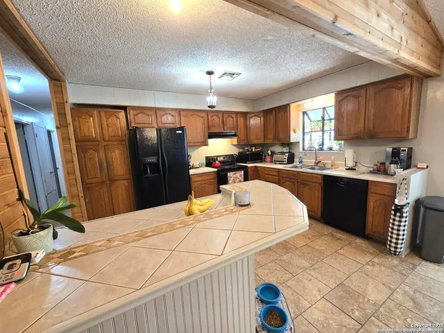 a kitchen with stainless steel appliances kitchen island granite countertop a table chairs in it and a window