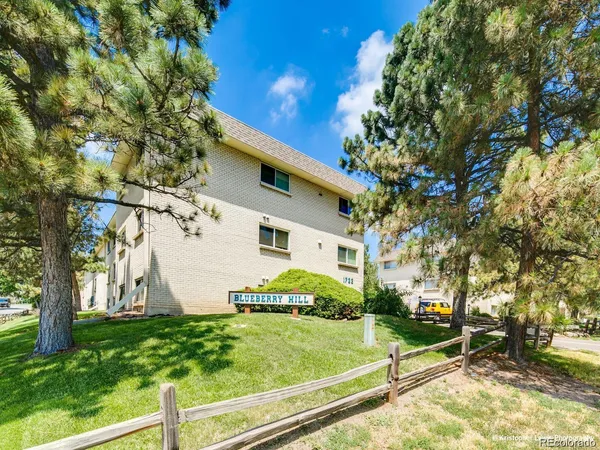 a view of a white house next to a yard with big trees