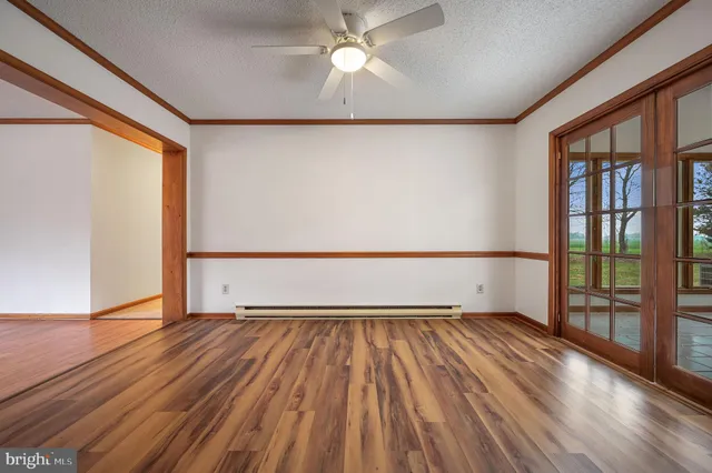 a view of empty room with wooden floor and fan